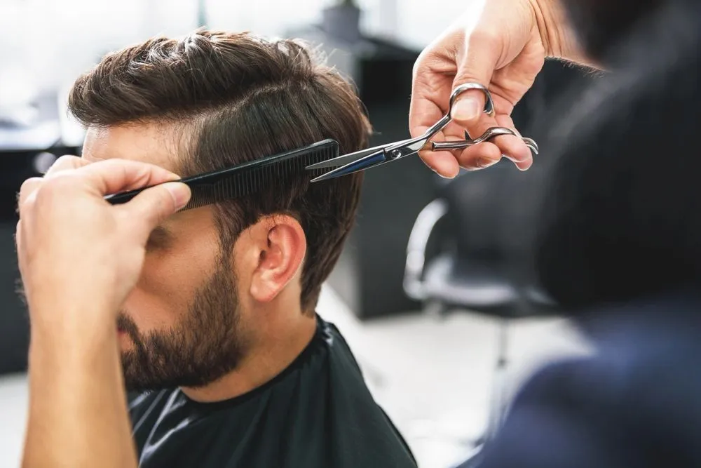 A stylist giving a guest a precision men's cut